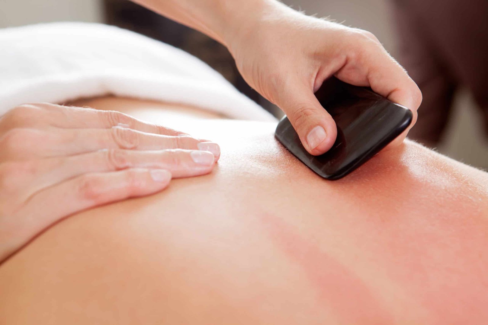 Close-up of a therapist performing gua sha on a person’s back.