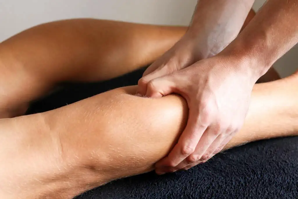 Close-up of hands performing lower body tissue work on a person’s leg.