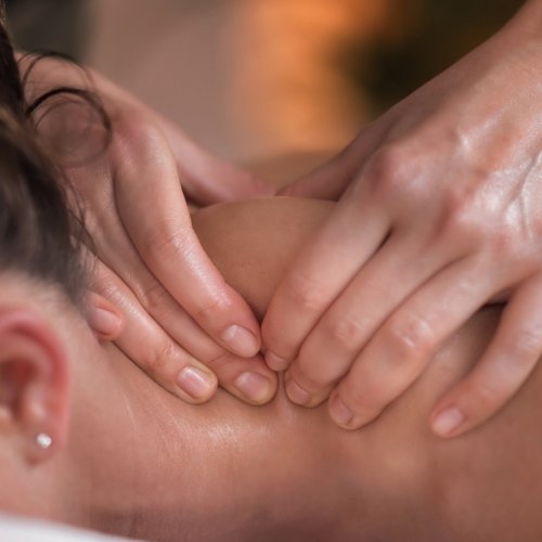 Close-up of hands performing tissue work on a person’s neck and shoulder.